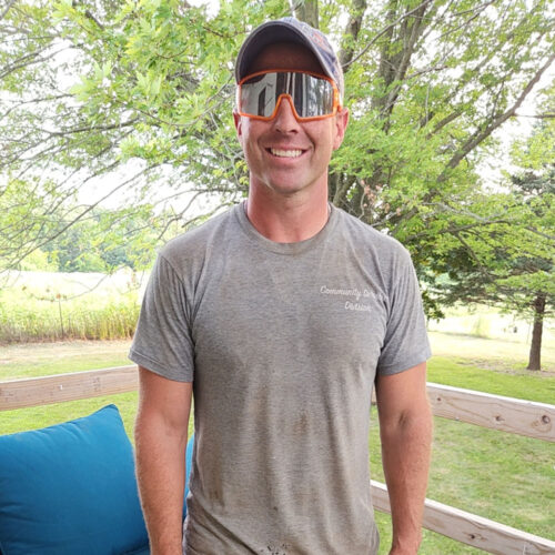 Anthony Clinton, co-founder of Clinton Dynamics, smiling outdoors in a casual t-shirt and cap.