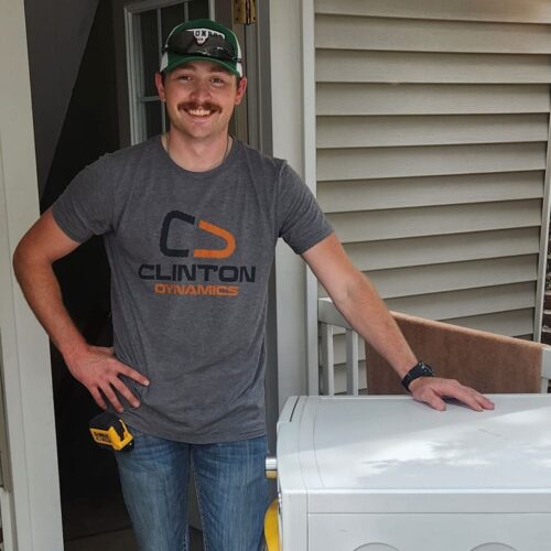 Tanner Clinton, co-founder of Clinton Dynamics, standing confidently in a Clinton Dynamics t-shirt, next to a project site.