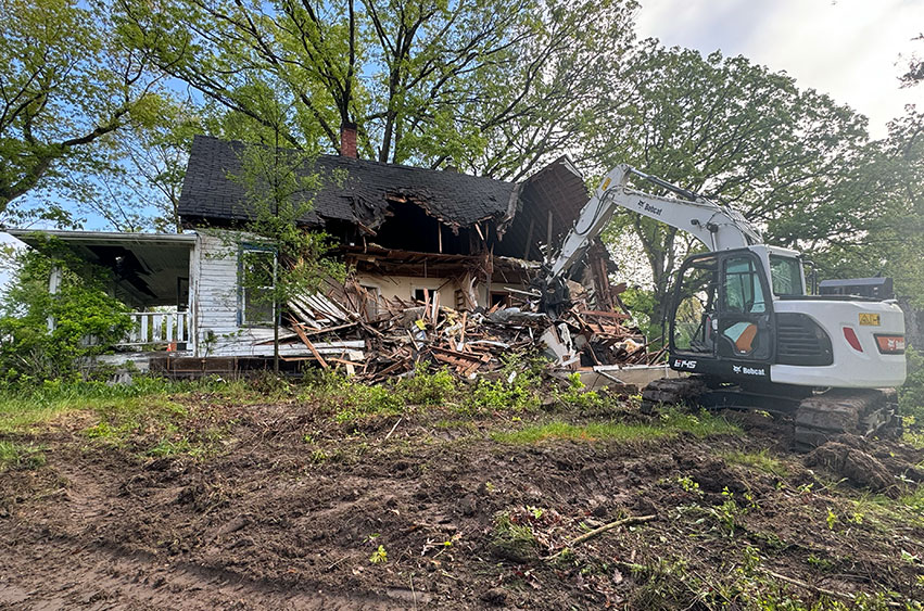 Excavator tearing down an old Iowa home during a residential demolition project.