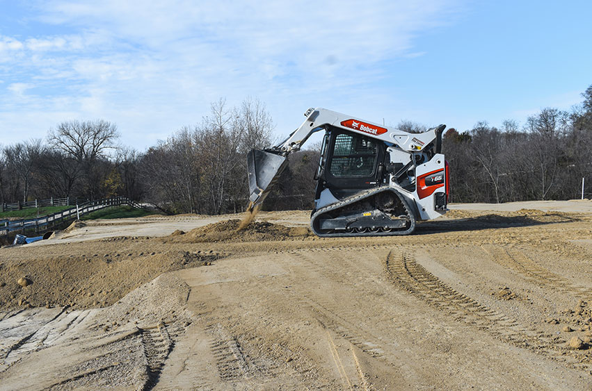 Bobcat loader spreading sand for a construction project in Iowa.