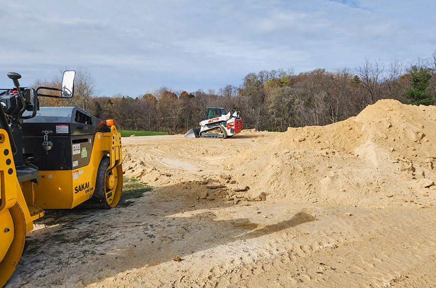 Heavy equipment compacting sand for a stable surface in Iowa.