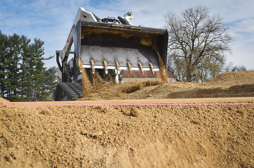 Bobcat loader distributing sand evenly for a finished project.