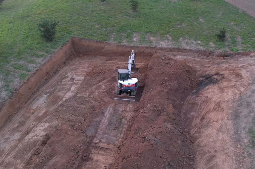 Excavator digging the initial trench for a shooting range site in Iowa.