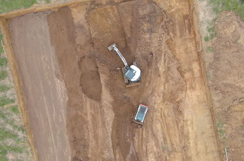 Top-down view of excavation progress with machines shaping the shooting range area.