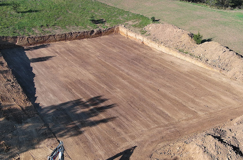 Completed excavation site for a shooting range with a leveled dirt foundation in Iowa.